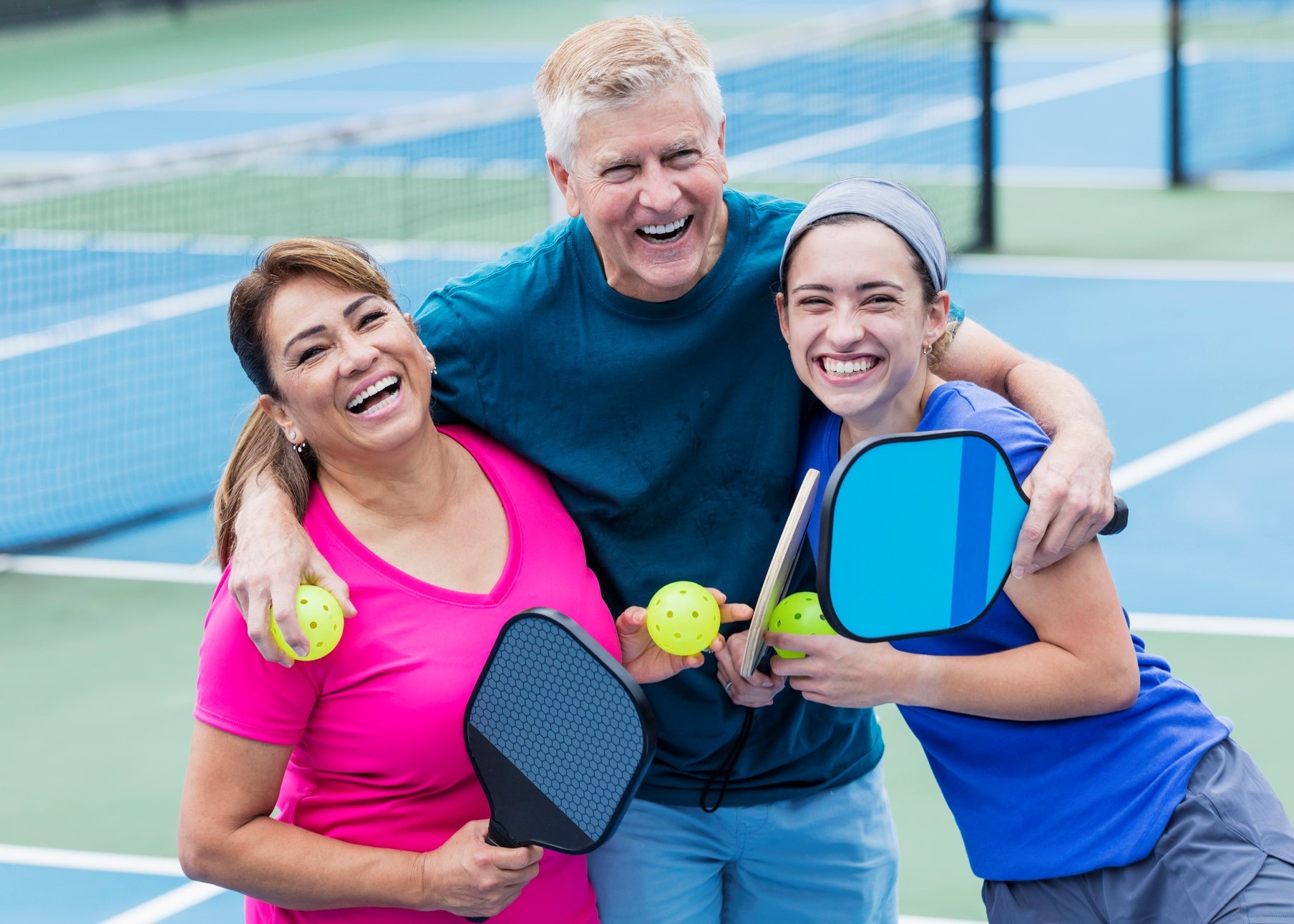 Couple and adult daughter playing pickleball